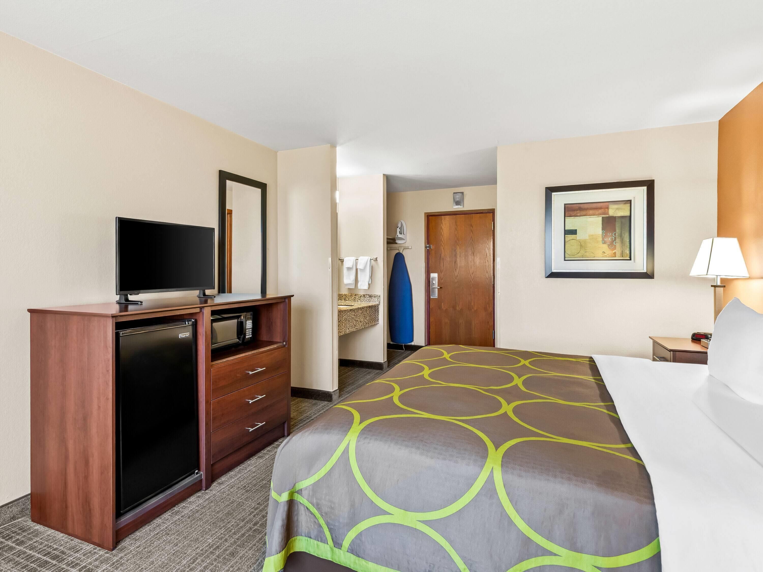 Une chambre d’hôtel avec un lit, une télévision, un bureau doté d’un micro-ondes et une salle de bain visible à travers une porte ouverte.
