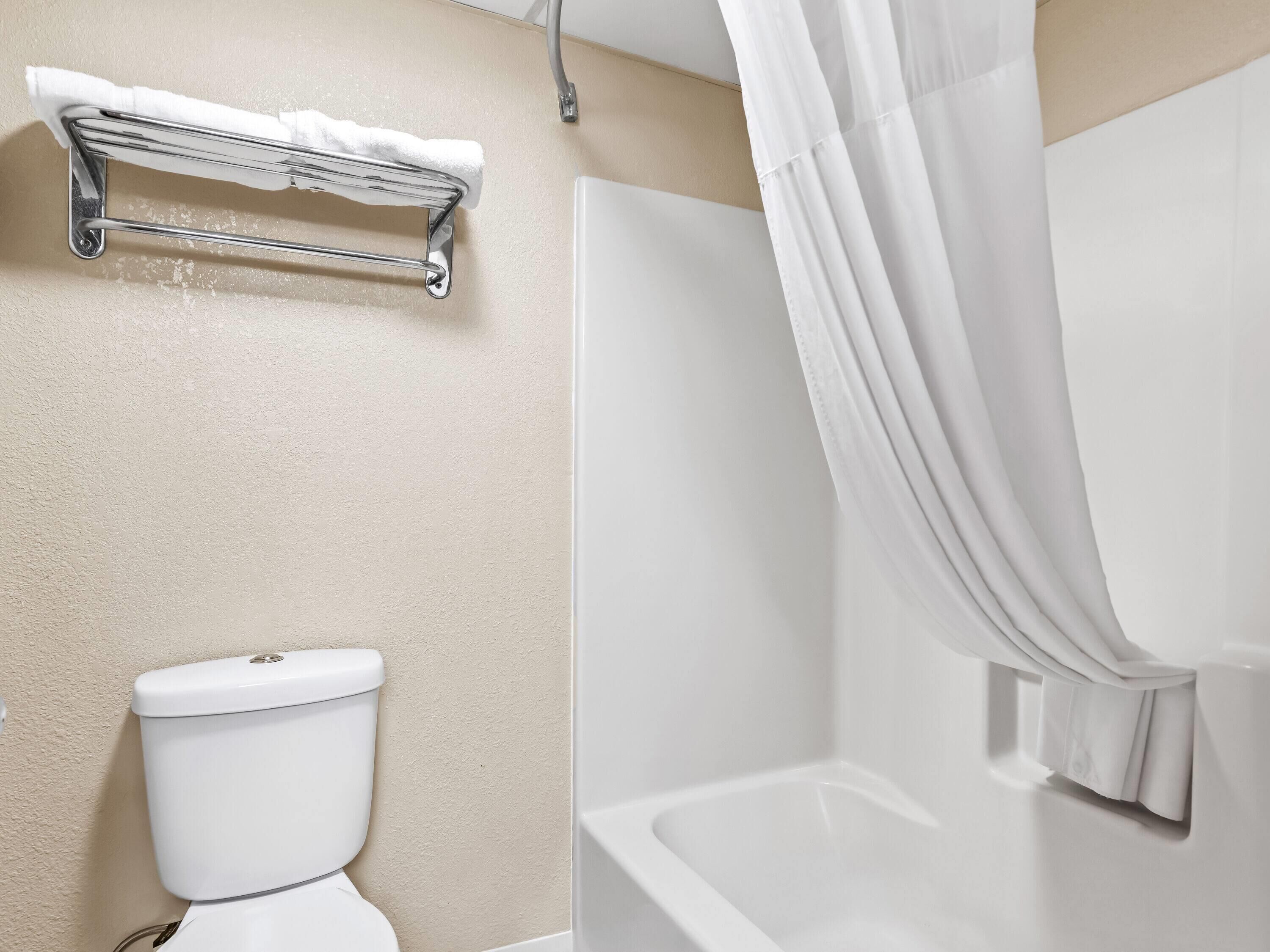 A bathroom with a toilet, a shower with a curtain, and a towel rack.