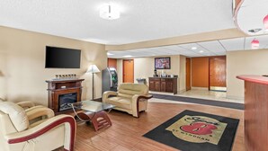 A hotel lobby with a fireplace, seating area, reception desk, and a flat-screen TV mounted on the wall. - Super 8 by Wyndham Sturtevant/Racine (Sturtevant)