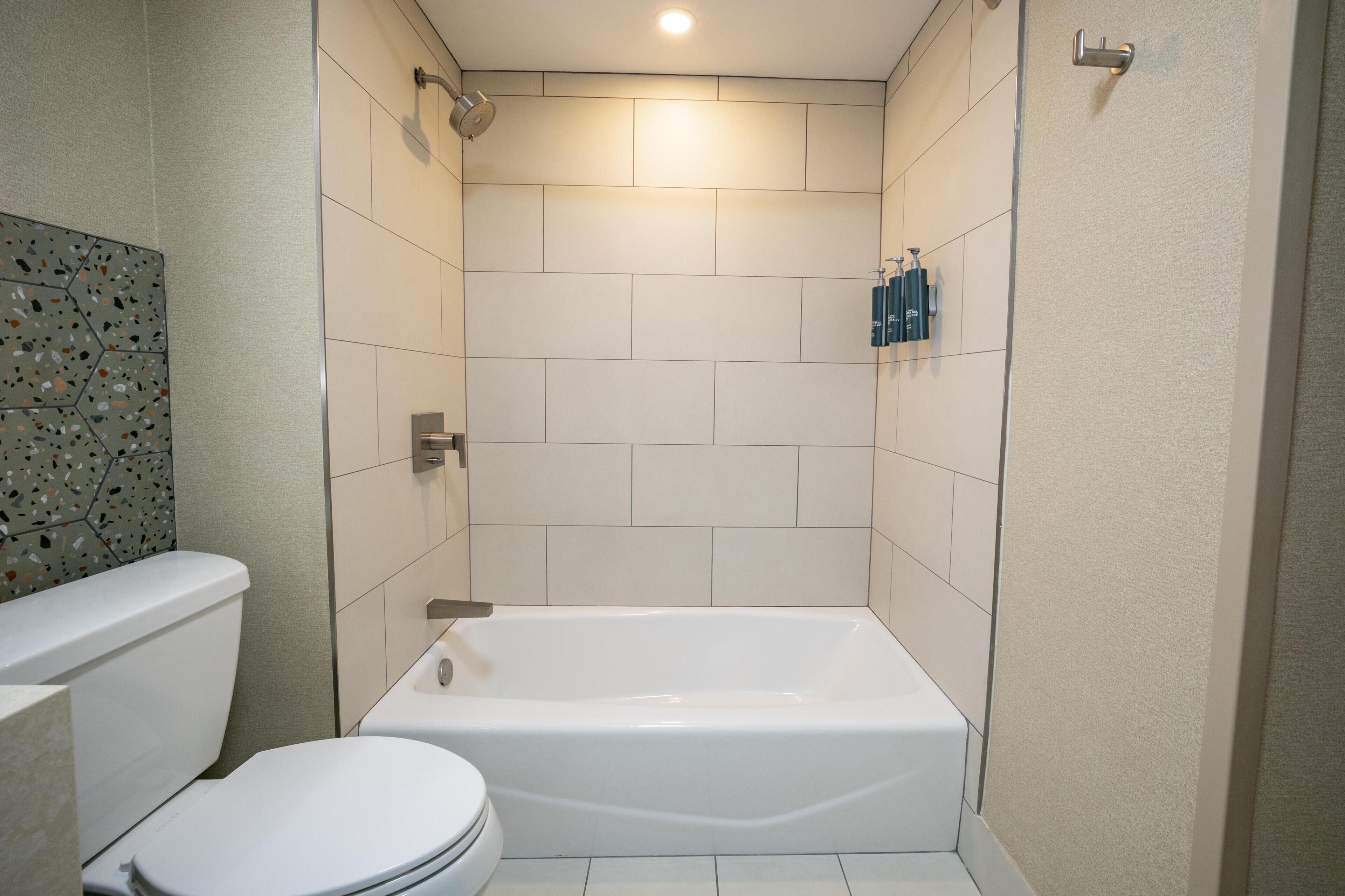 A bathroom with a white bathtub, a toilet, and a shower.