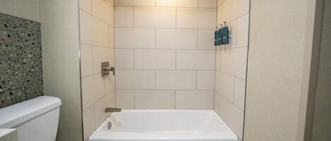 A bathroom with a white bathtub, a toilet, and a shower.