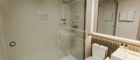 Une salle de bain moderne avec une douche à parois de verre, des toilettes et un lavabo avec un miroir au-dessus.