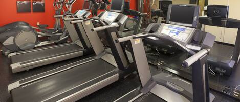 Une salle de sport équipée de plusieurs tapis de course, de vélos d’appartement et d’appareils elliptiques.