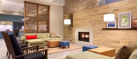 Una sala moderna con chimenea, paneles de madera y un comedor al fondo.