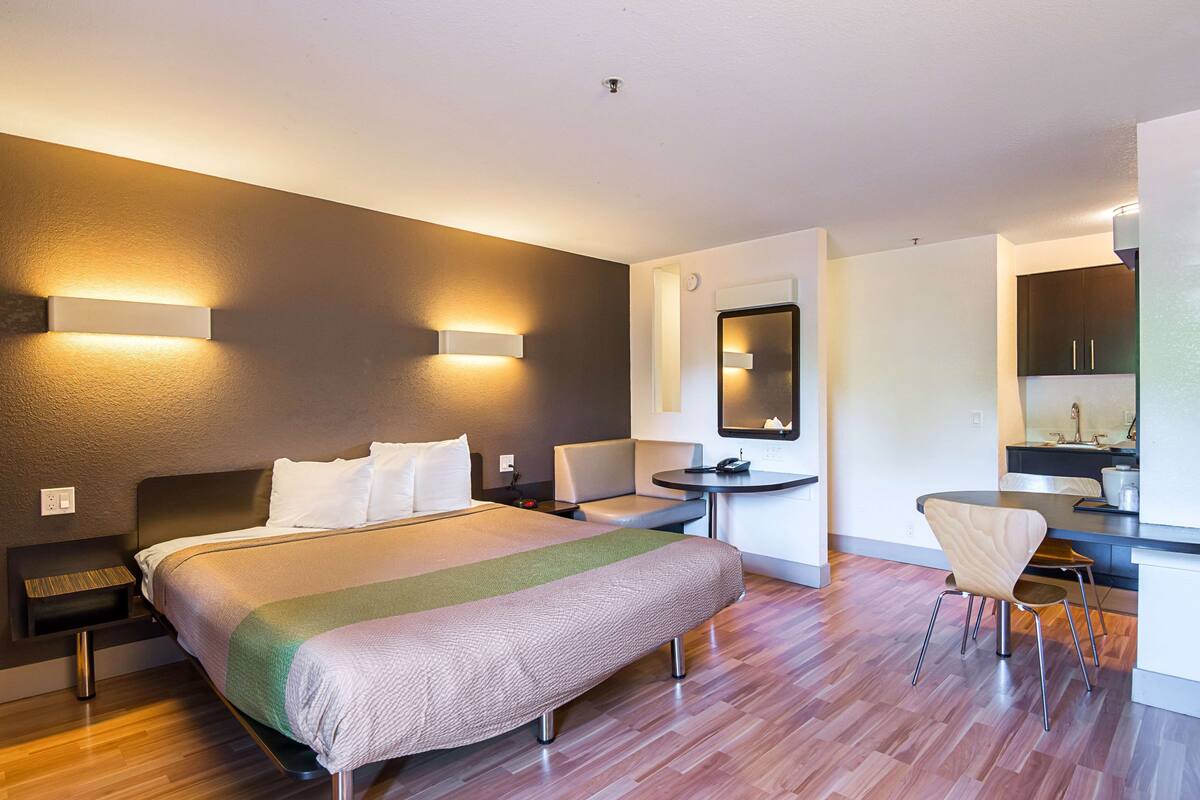 A modern hotel room with a large bed, bedside tables, a desk, and a chair.