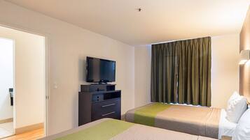 Habitación de hotel con dos camas, un televisor en una cómoda y una ventana con cortinas.
