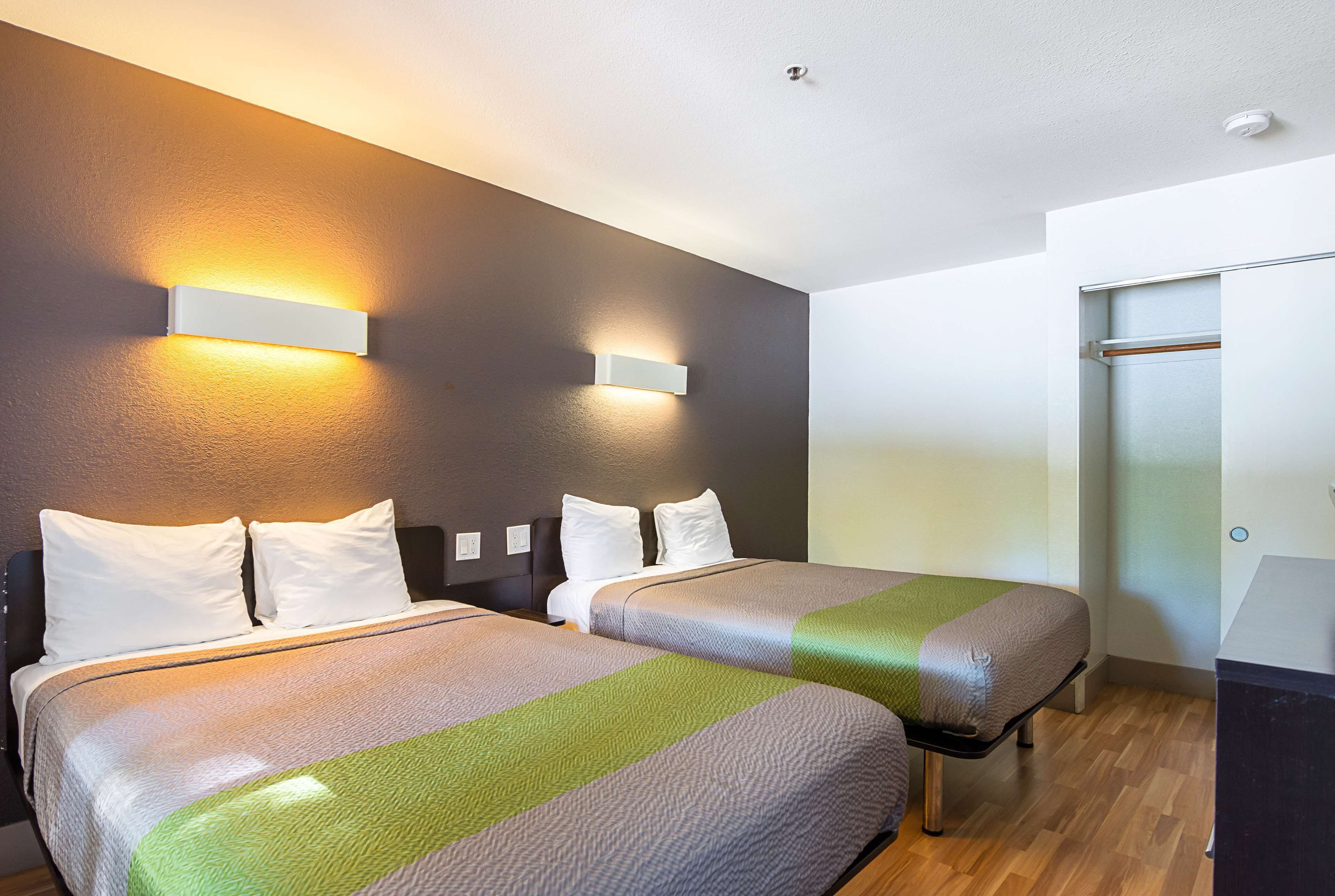 A hotel room with two beds, a wardrobe, and a sliding door.