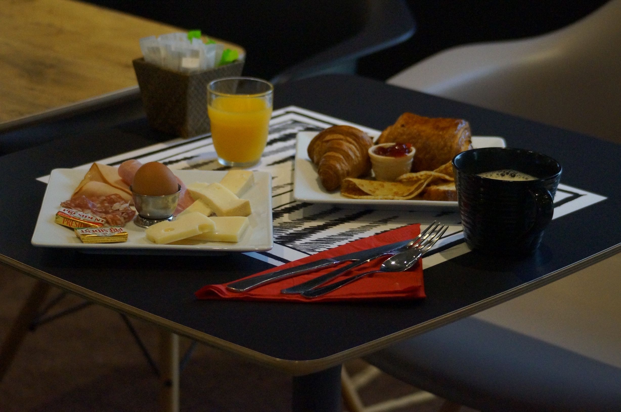 Una tavola imbandita con croissant, formaggio, uova e un bicchiere di succo d'arancia.