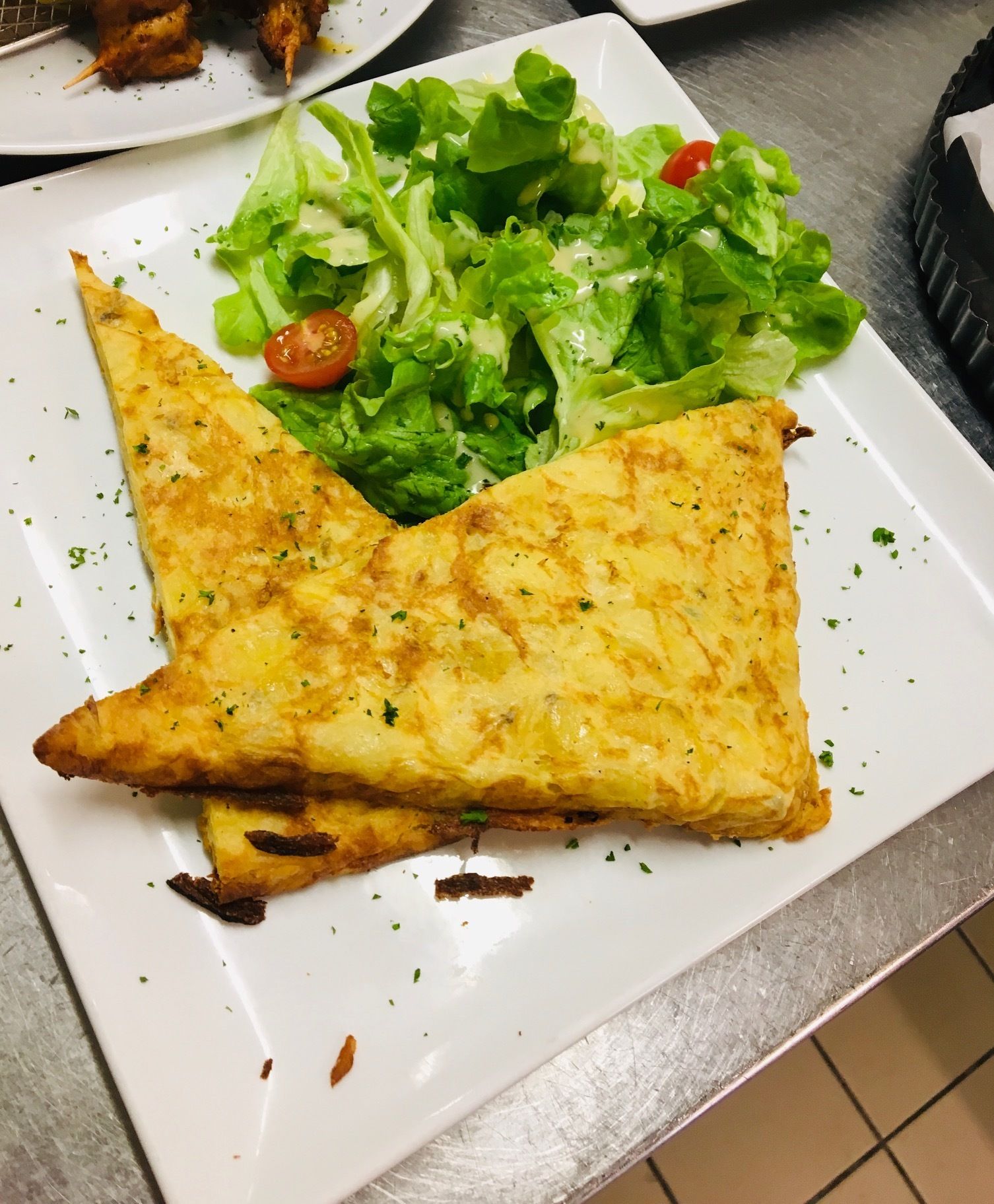 A plate with a triangular pastry and a side salad.
