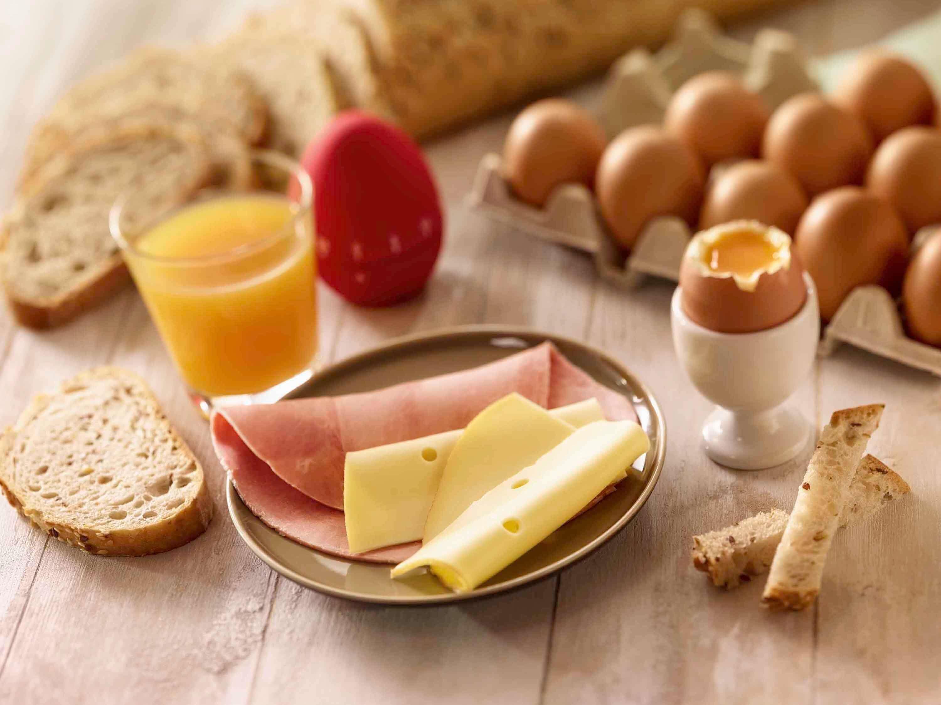 A breakfast setting with bread, eggs, cheese, and a glass of orange juice.