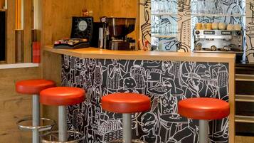 A bar area with a counter, stools, and a coffee machine.