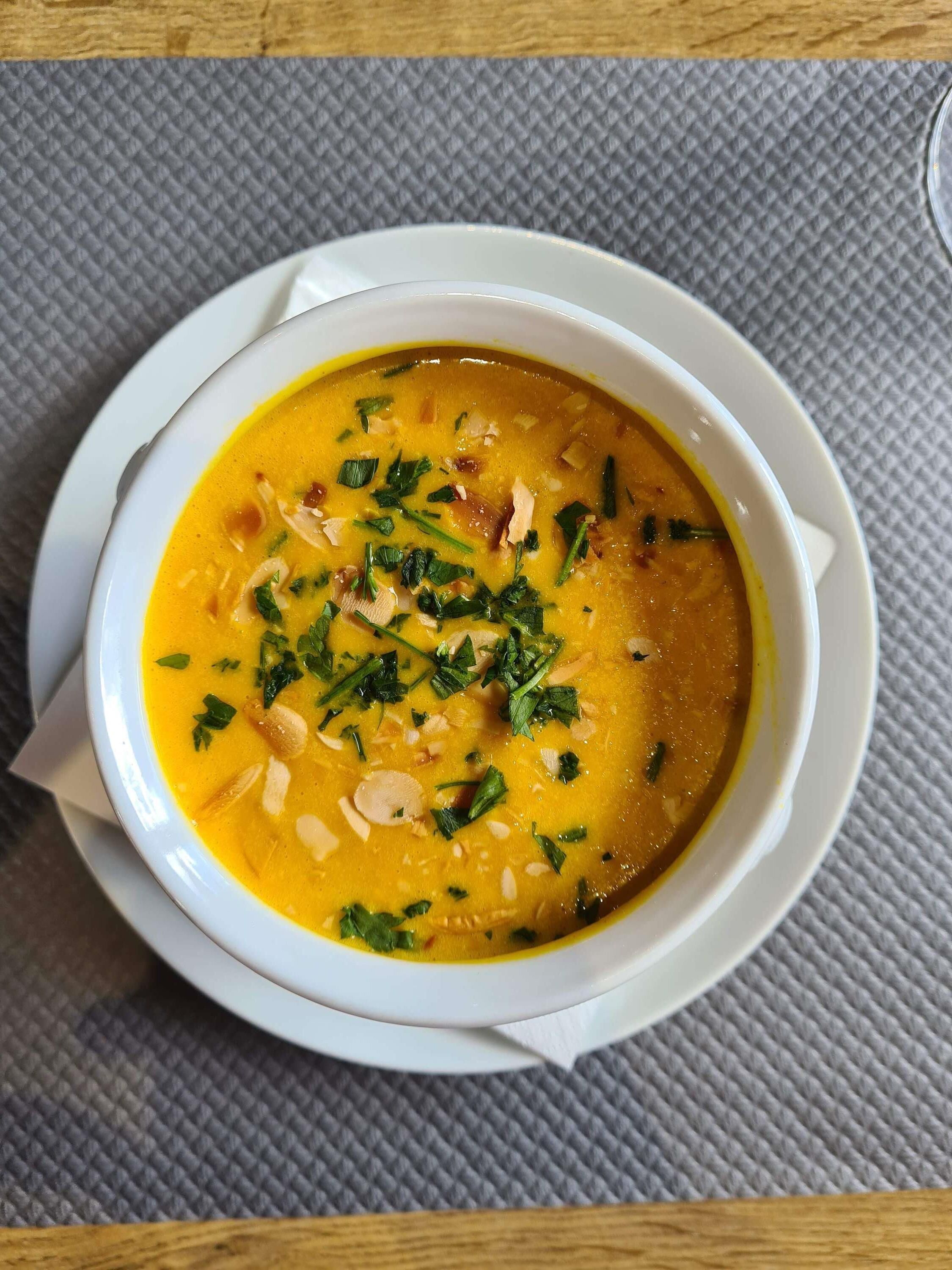 A bowl of soup with a white bowl on a textured tablecloth.