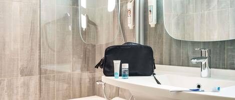 A modern bathroom with a glass shower enclosure, a white sink with a mirror, and a towel rack.