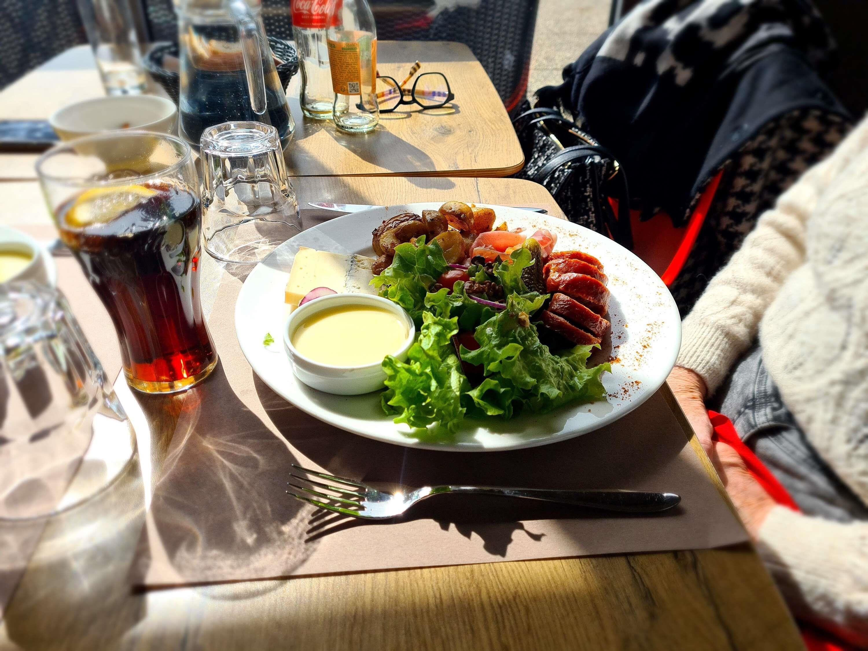 A dining table with a plate of food, a glass of beverage, and a fork.