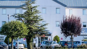 Un hotel dal design moderno, con un cartello ben visibile, un'area parcheggio e un prato curato.
