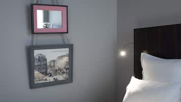 A bedroom with a bed, a headboard, and two framed pictures on the wall.