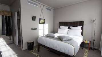 A bedroom with a bed, bedside table, lamp, and a small stool.