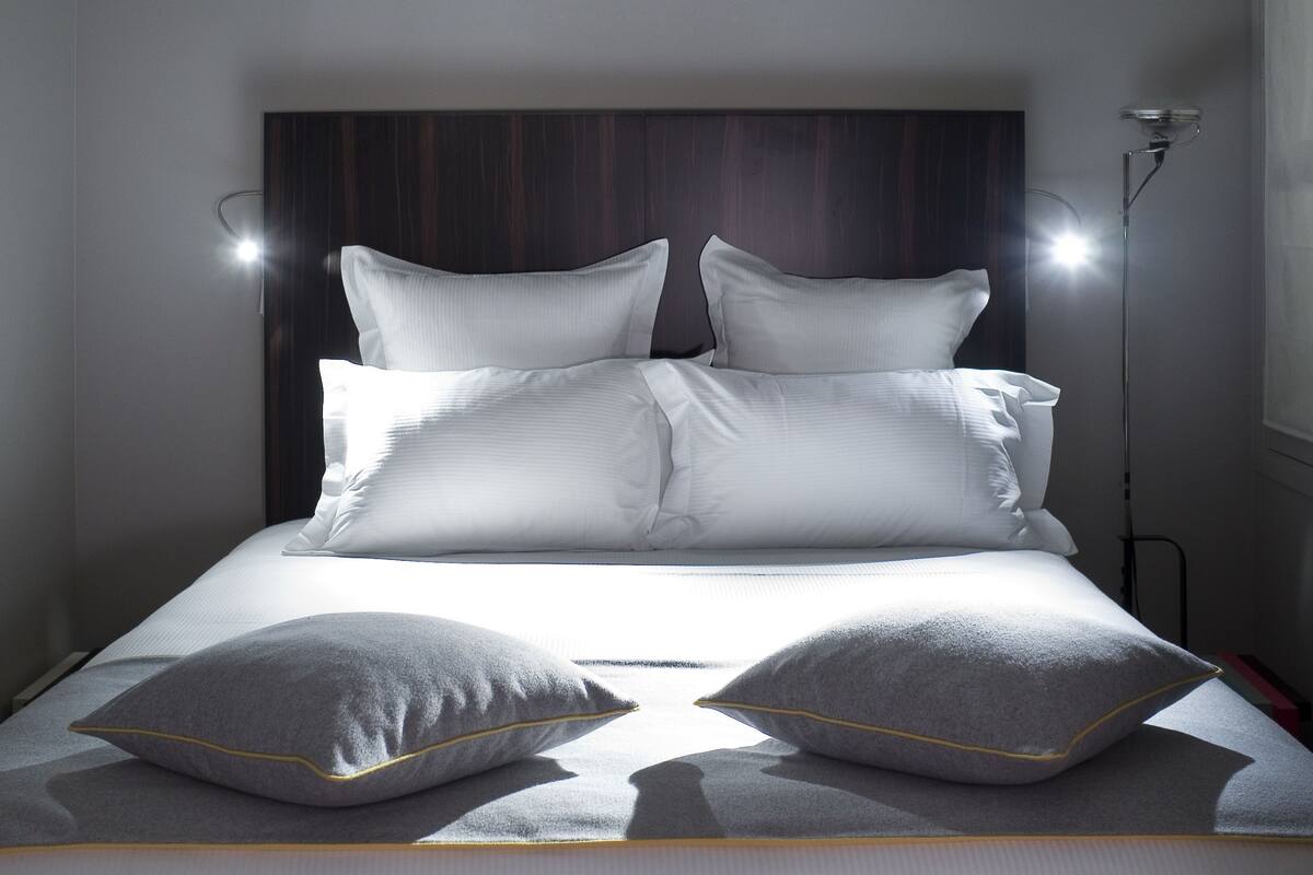 A neatly made bed with white bedding and two grey pillows.