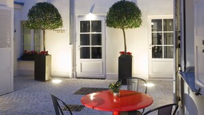 A courtyard with a red table and chairs, two potted trees, and a sign indicating 'Chambres Paired Even Rooms'. - Hotel Saint Dominique (Paris)