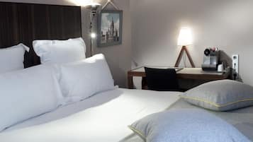 Camera d'albergo con un letto grande, una scrivania con una lampada e una macchina per caffè.