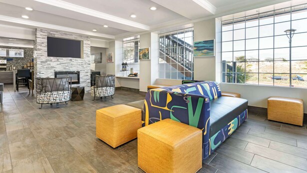 A spacious living area with a modern fireplace, comfortable seating, and large windows offering a view of the beach. - Best Western Marina State Beach (Marina)