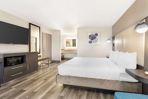 Relax in a serene space with a large bed, flat-screen TV, and bench.
