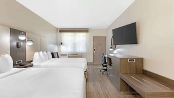 Une chambre d’hôtel avec deux lits, un bureau, un téléviseur à écran plat et une fenêtre avec des stores.
