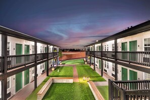 Stroll through the serene courtyard, surrounded by lush green lawns and a tranquil pathway.
