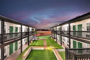 Stroll through the serene courtyard, surrounded by lush green lawns and a tranquil pathway.