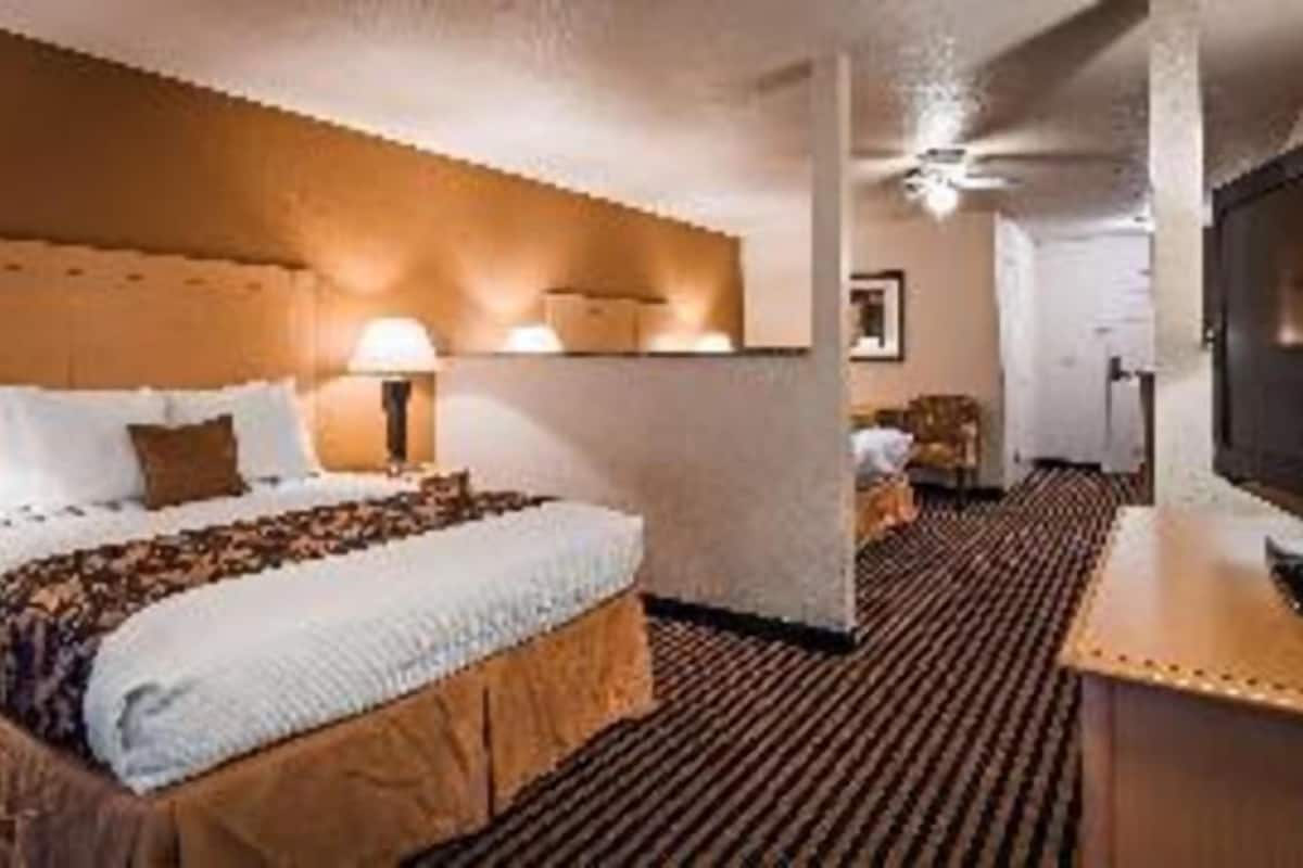 A hotel room with a bed, a desk, a television, and a chair.