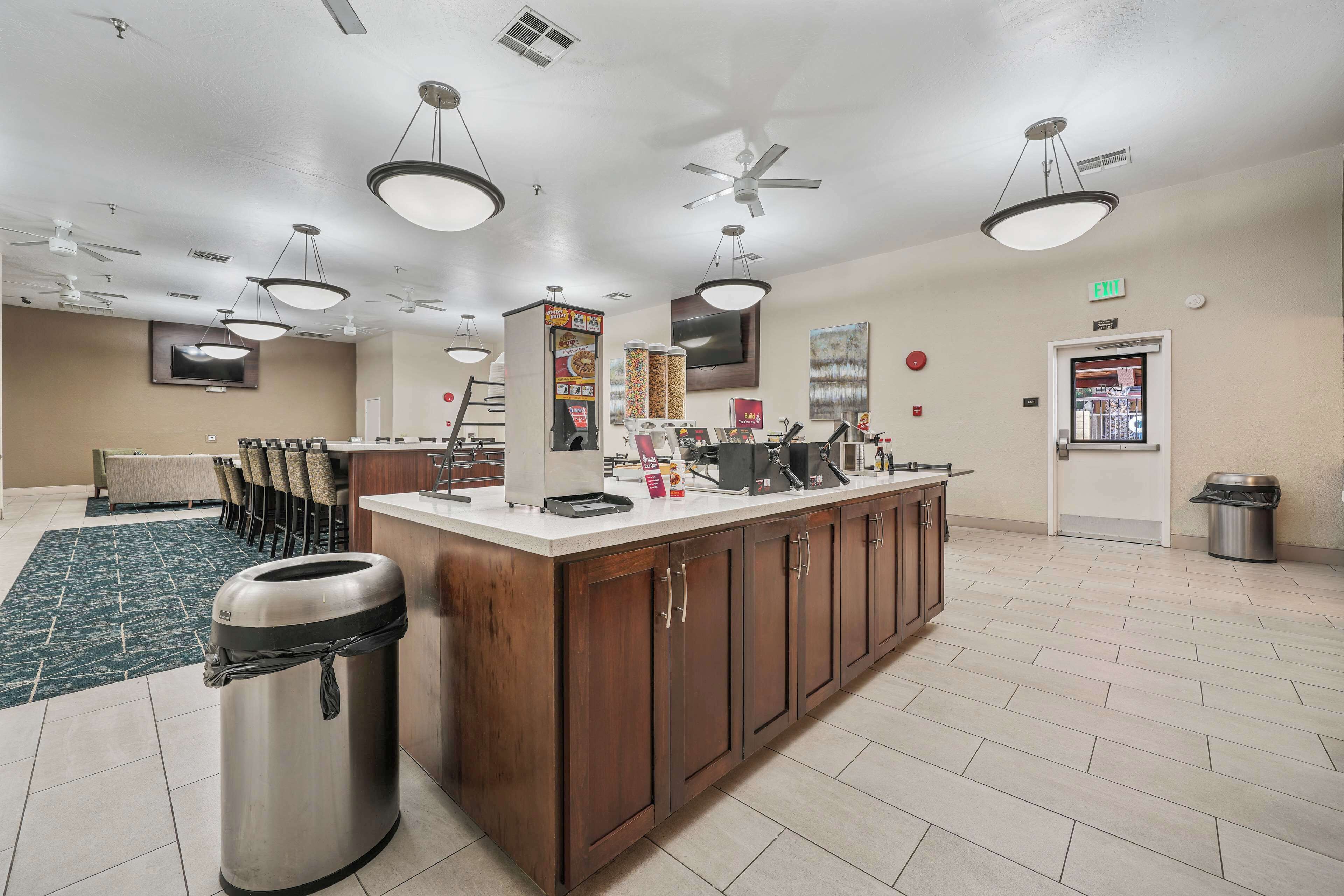 A hotel kitchen with a central island, ceiling fans, and a trash can.