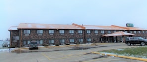 A motel with a brick facade, multiple windows, and a covered parking area.