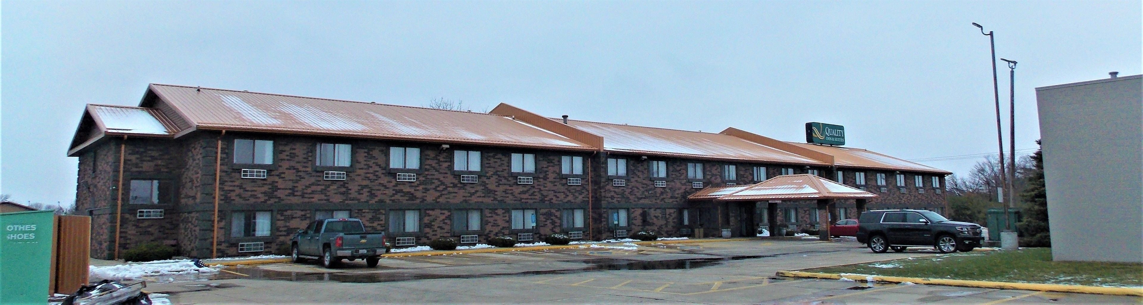 A building with a brick facade and a metal roof. There are several windows and a sign indicating it is a hotel.