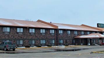 A building with a brick facade and a metal roof. There are several windows and a sign indicating it is a hotel.