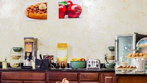 Ein Frühstücksbuffet mit Waffeln und Äpfeln, einem Waffeleisen, einem Toaster und einer Kaffeemaschine.