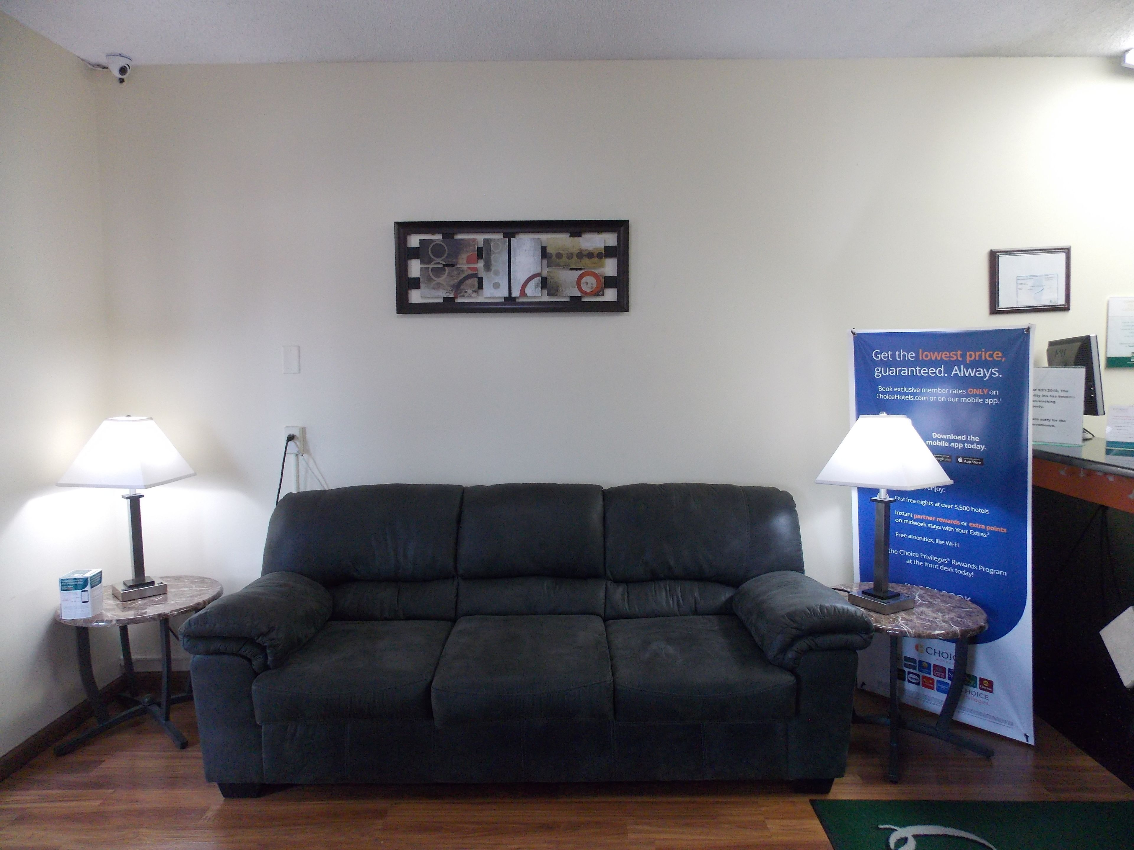 A dark leather sofa in a room with two lamps on either side. A framed artwork hangs on the wall above the sofa.