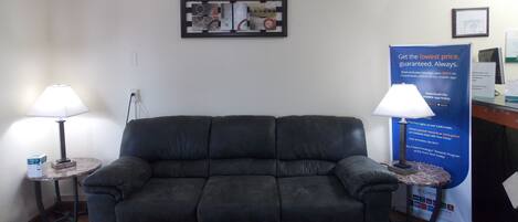 A dark leather sofa in a room with two lamps on either side. A framed artwork hangs on the wall above the sofa.
