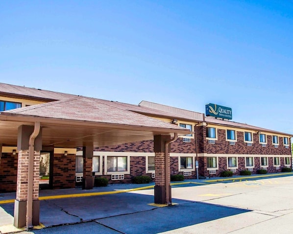 A hotel with a covered entrance, brick facade, and a sign for Quality Inn & Suites.