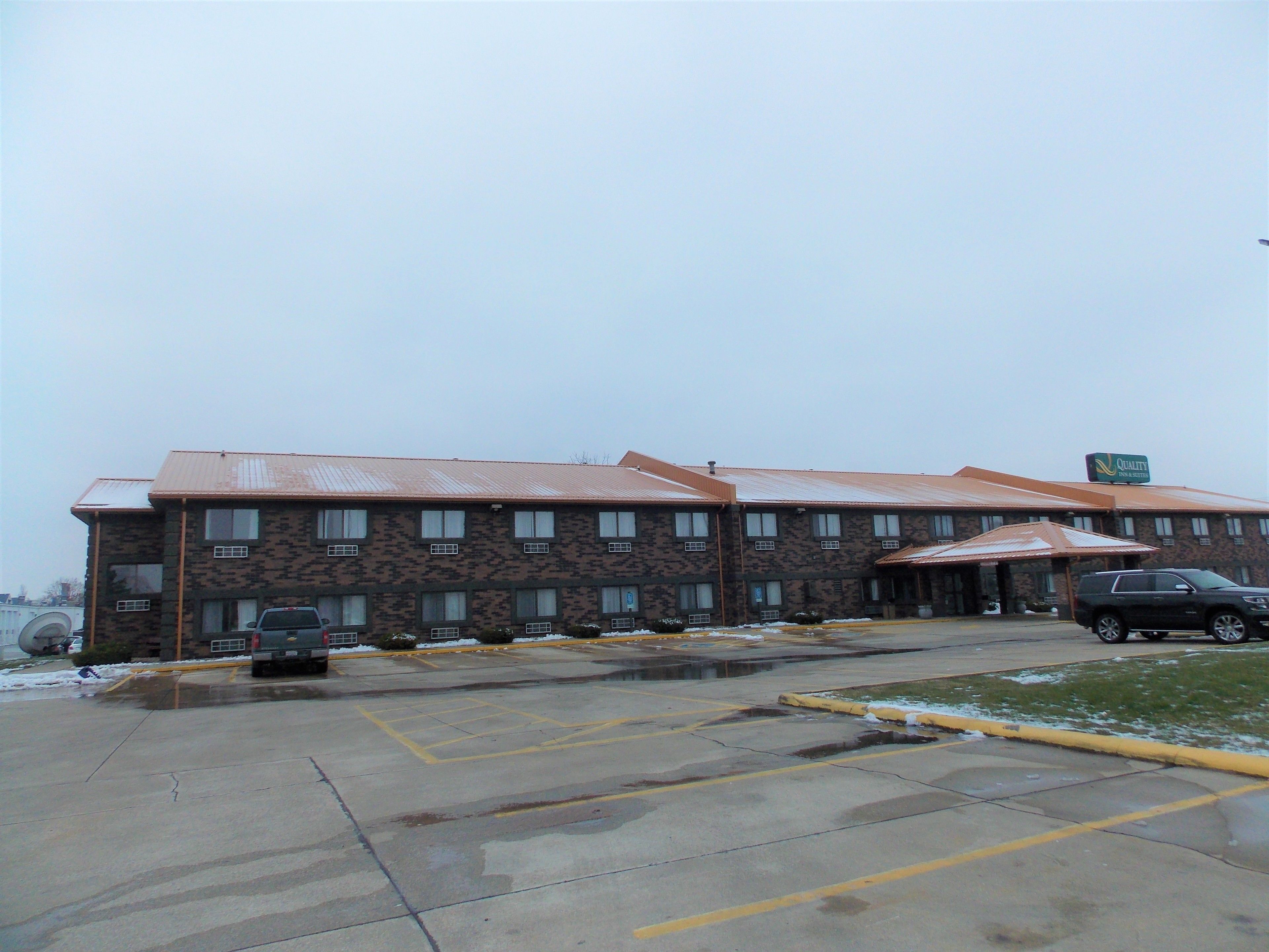 A multi-story building with a patterned facade, a parking lot with marked spaces, and a sign indicating a hotel.