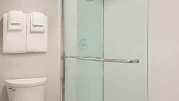 Une salle de bain avec une douche à parois de verre, des toilettes et deux serviettes suspendues à un porte-serviettes.