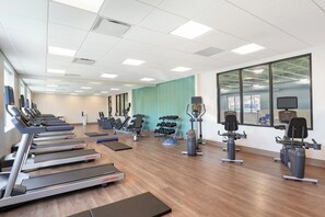 A gym with treadmills, elliptical machines, and weight stations.