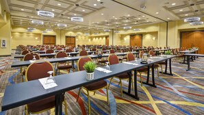 Ein großer Konferenzraum mit mehreren Tischen und Stühlen, ausgestattet mit Mikrofonen und Namensschildern, in einem Hotel.