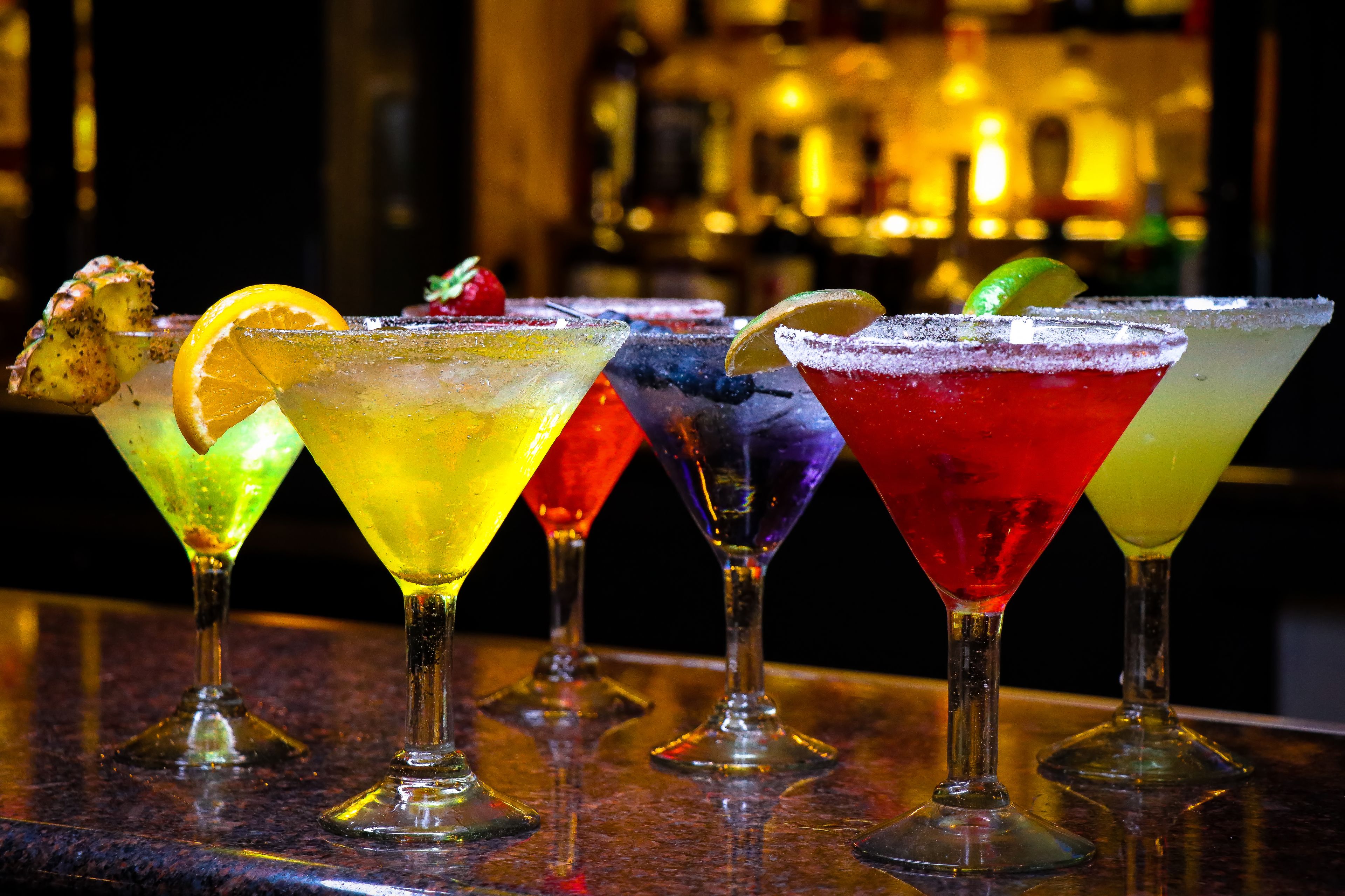 A bar with various colorful cocktails in martini glasses.