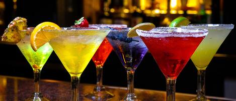 A bar with various colorful cocktails in martini glasses.