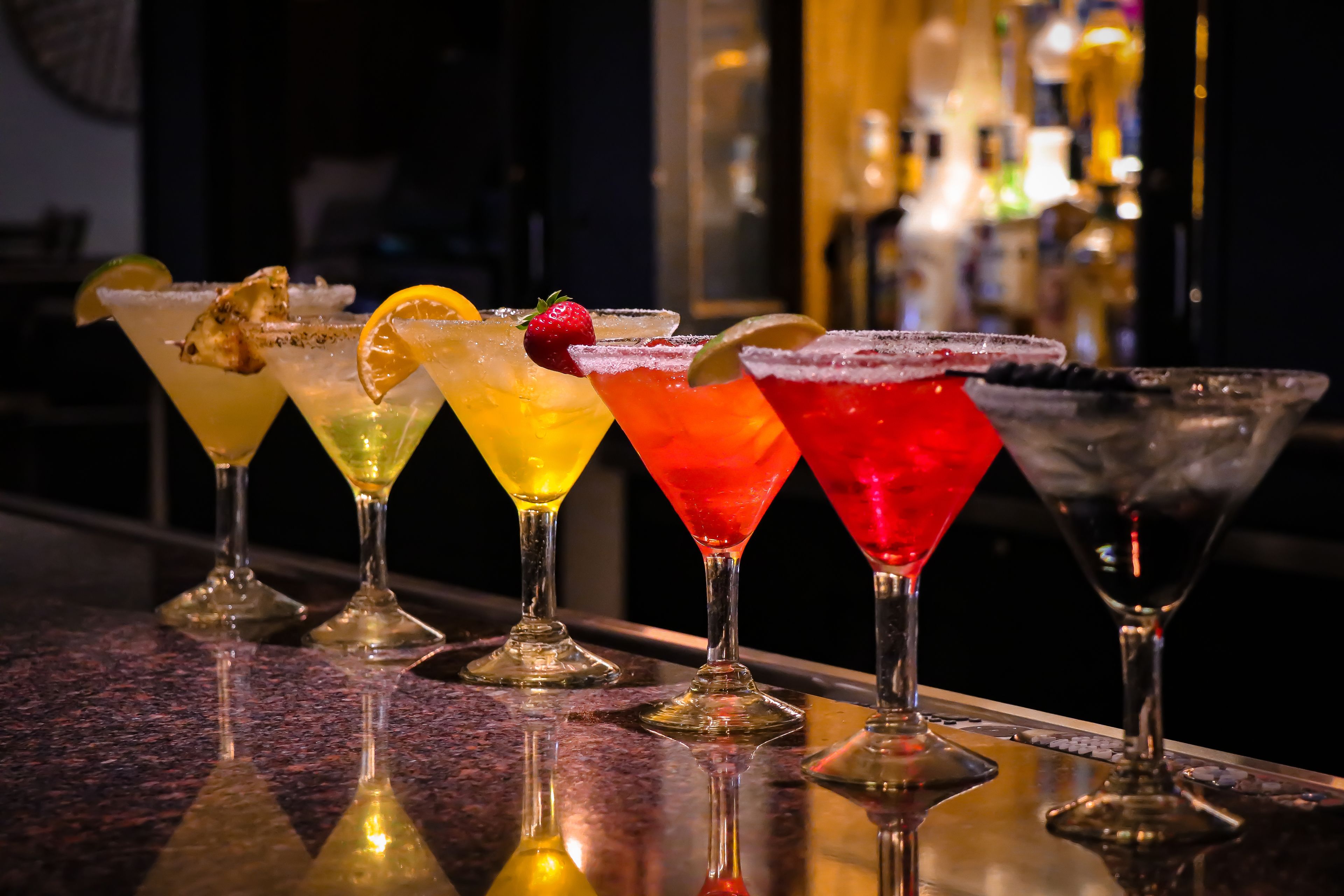 A bar with a variety of colorful cocktails, each garnished with different fruits and a salted rim.