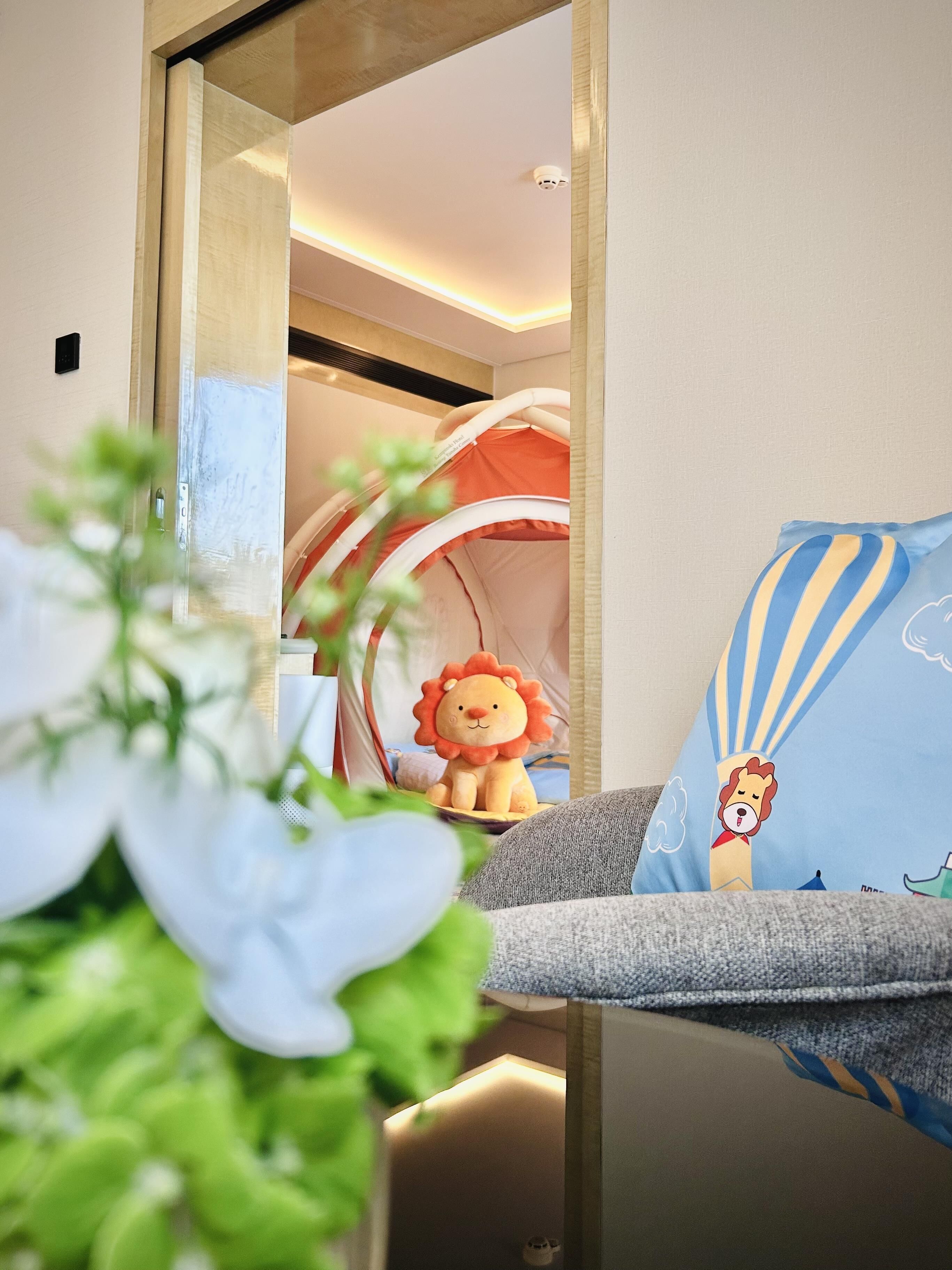 Zona de juegos infantiles con una tienda de campaña y un león de peluche.