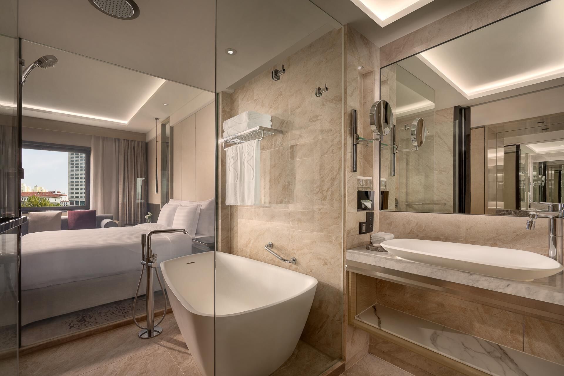 Une salle de bain d’hôtel moderne, dotée d’une grande baignoire, d’une douche séparée et d’un meuble-lavabo.