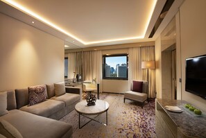 A modern hotel room with a sofa set, a round coffee table, a TV, and a window with a city view. - Kempinski Hotel Beijing Yansha Center (Beijing)