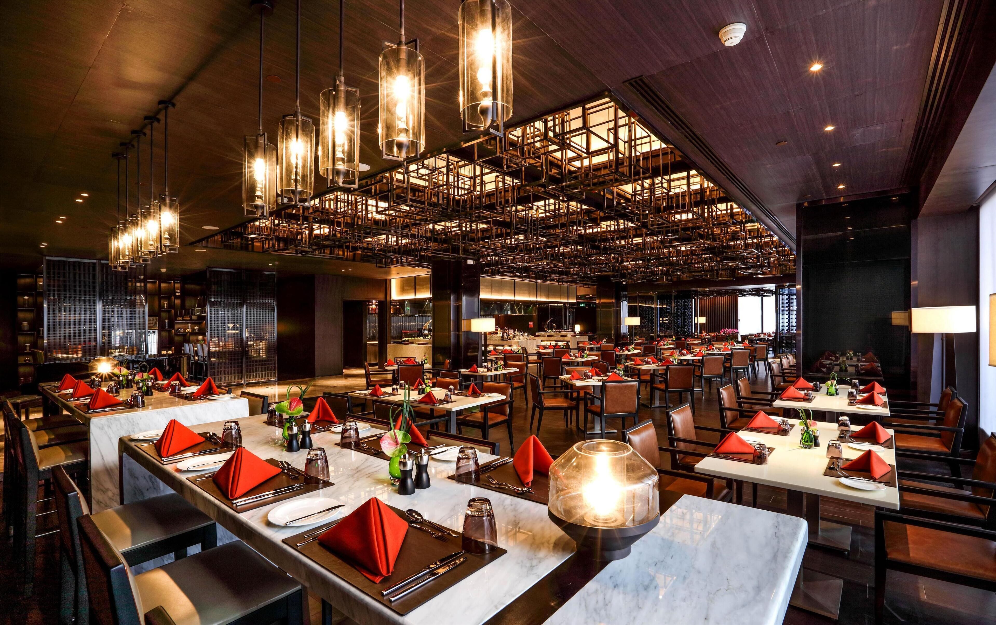 A spacious restaurant with high ceilings, multiple dining areas, and modern lighting fixtures.