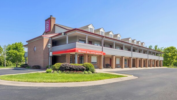A two-story Red Roof Inn & Suites building with a brick facade, multiple windows, and a covered entrance.